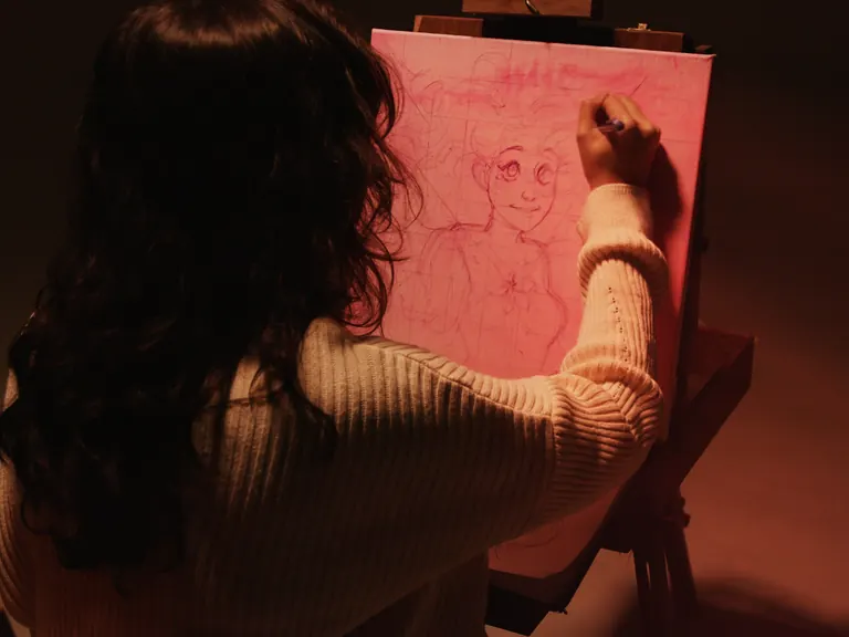 Mano dibujando sobre papel rosado